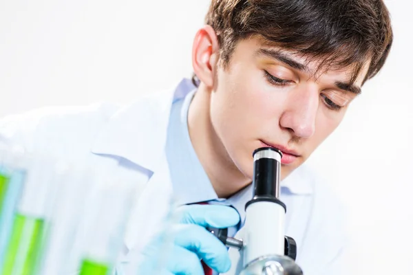 Bielony naukowiec patrząc pod mikroskopem — Zdjęcie stockowe