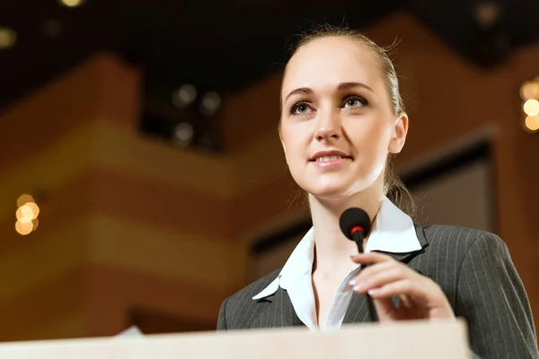 Zakenvrouw spreekt in een microfoon — Stockfoto