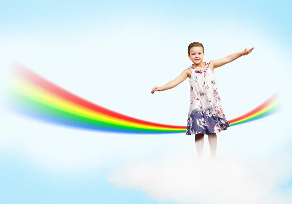 Chica saltando sobre las nubes y un arco iris — Foto de Stock