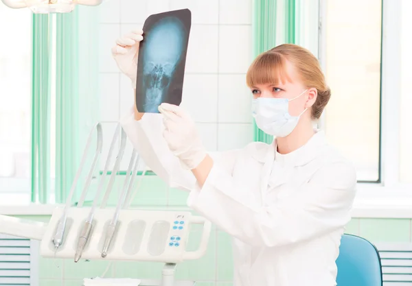 Jeune femme médecin regarde une radiographie du crâne — Photo