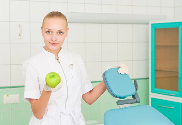 Vrouwelijke tandartsen toont groene appel — Stockfoto