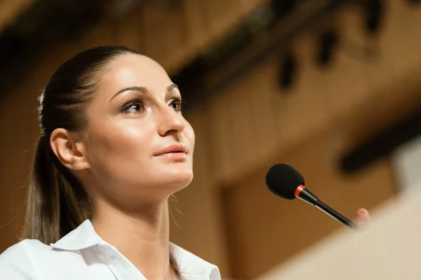 Business woman speaks into a microphone — Stock Photo, Image