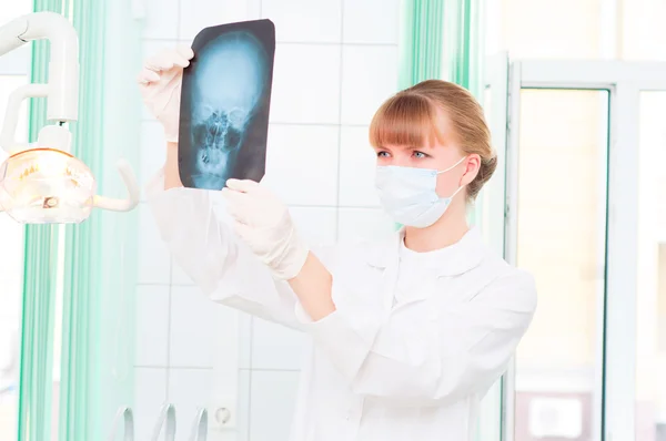 Young woman doctor looks at an X-ray of skull — Stock Photo, Image