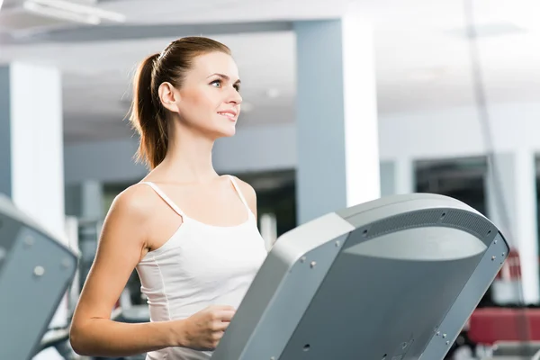 Attractive young woman runs on a treadmill — Stock Photo, Image