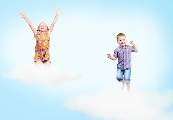 Mädchen und Junge auf Wolken und einem Regenbogen — Stockfoto