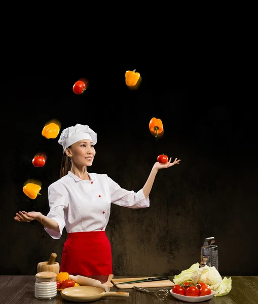 Woman-cook juggleing vegetables. — Stock Photo, Image