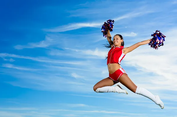 Giovane cheerleader in costume rosso saltando — Foto Stock