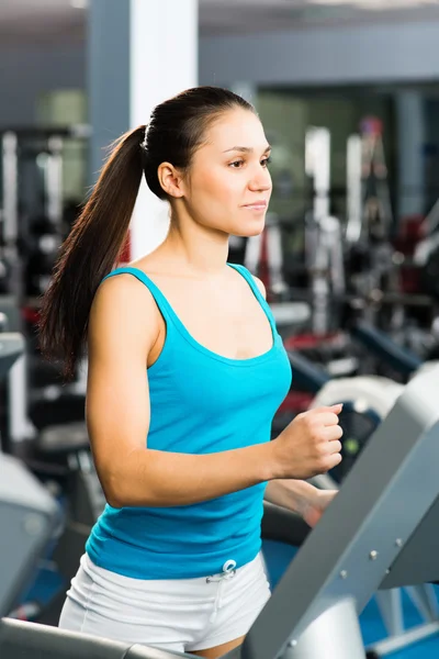 Attractive young woman runs on a treadmill — Stock Photo, Image