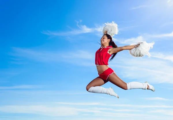 Młoda cheerleaderka w czerwony strój Skoki — Zdjęcie stockowe