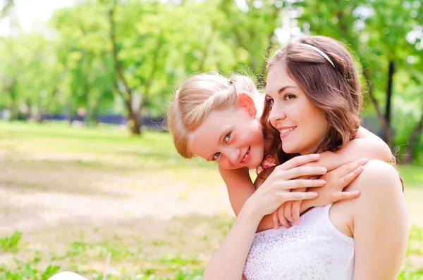 Anne ve kızı birlikte çimlerde oturan — Stok fotoğraf