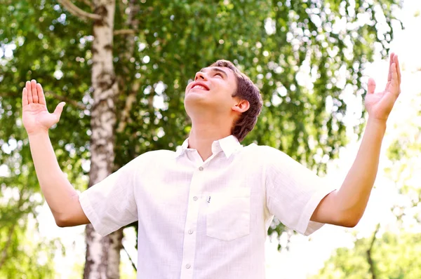 Young man looking to the sky, holding his hands up — Stock Photo, Image