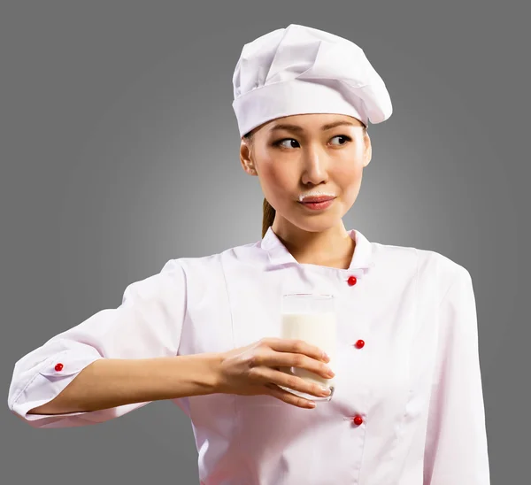 Female asian chef holding a glass of milk — Stock Photo, Image