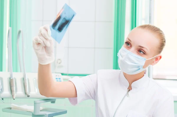 Woman doctor in protective mask looking at x-ray — Stock Photo, Image