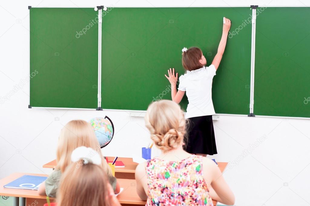 School girl writes on the blackboard