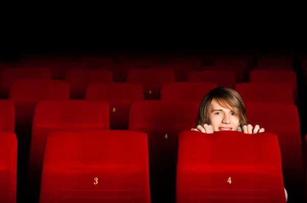 Jovem no cinema escondido atrás de uma cadeira — Fotografia de Stock