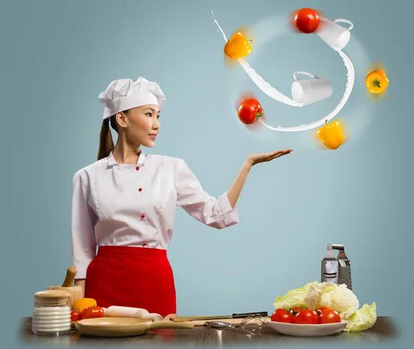 Азиатка-повар жонглирует овощами — стоковое фото