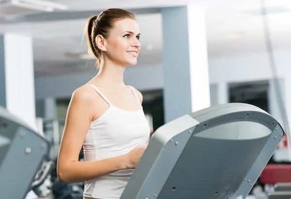 Attractive young woman runs on a treadmill — Stock Photo, Image