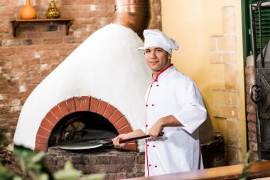 Şef, pizza fırını hamur koyar.,