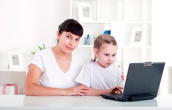 Mãe e filha estão trabalhando juntas para um laptop — Fotografia de Stock