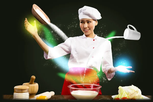 Asian female chef in the kitchen conjures — Stock Photo, Image