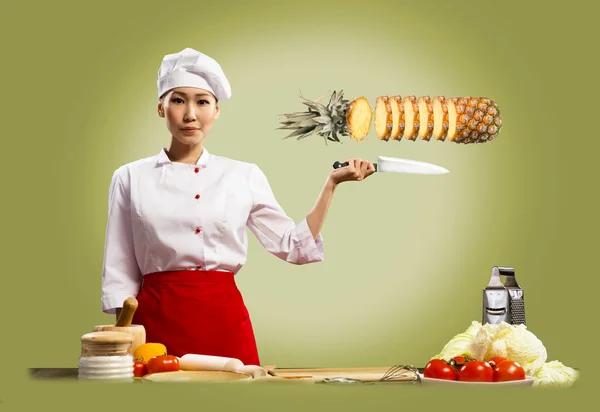 Asiatiska kvinnliga kock skär ananas — Stockfoto