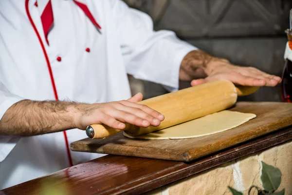 Cocinar despliega la masa en una tabla — Foto de Stock