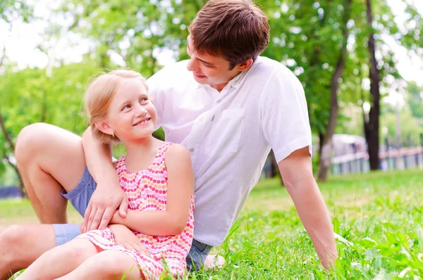 Far och dotter sitter tillsammans på gräset — Stockfoto