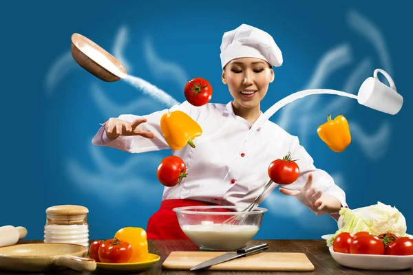 Asian female chef in the kitchen conjures — Stock Photo, Image