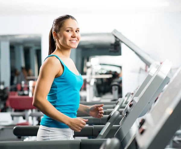 Attractive young woman runs on a treadmill — Stock Photo, Image