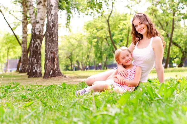 Anne ve kızı birlikte çimlerde oturan — Stok fotoğraf