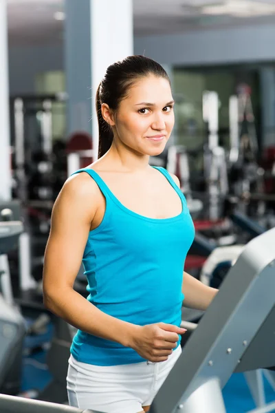 Attractive young woman runs on a treadmill — Stock Photo, Image