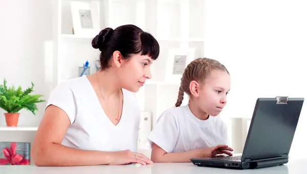 Mom and daughter are working together for a laptop