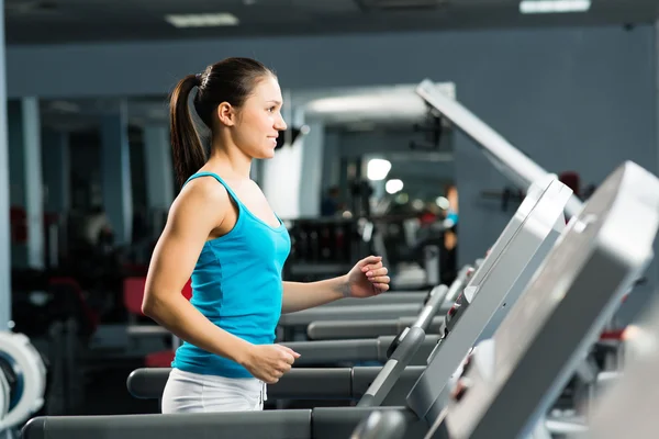 Attractive young woman runs on a treadmill — Stock Photo, Image