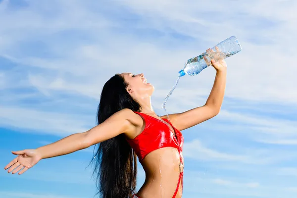 Спортивная девушка в красной форме с бутылкой воды — стоковое фото