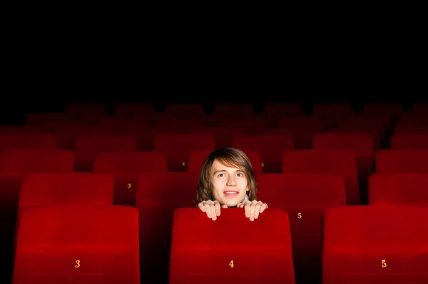Jovem no cinema escondido atrás de uma cadeira — Fotografia de Stock