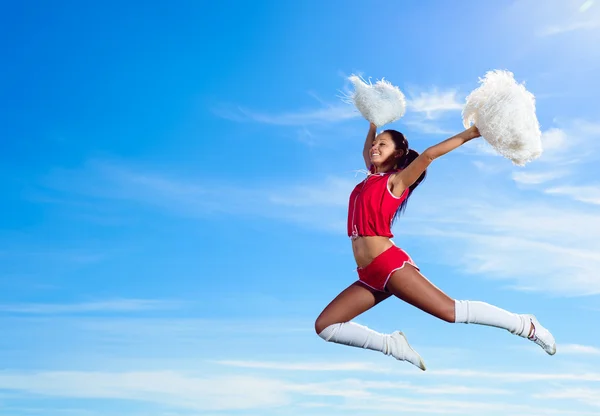 Młoda cheerleaderka w czerwony strój Skoki — Zdjęcie stockowe