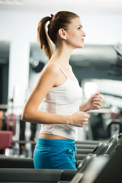 Attractive young woman runs on a treadmill — Stock Photo, Image