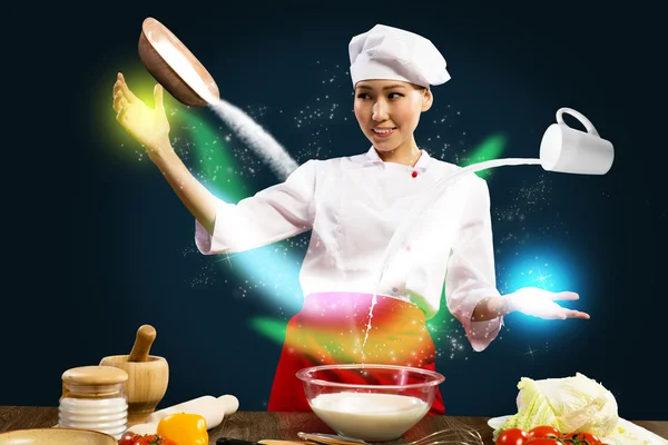 Asian female chef in the kitchen conjures — Stock Photo, Image