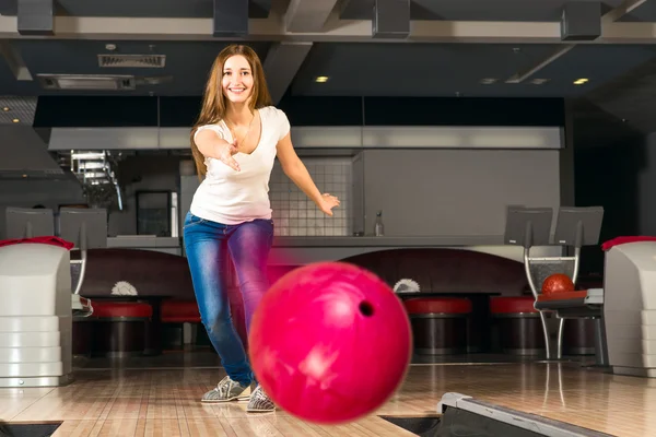 Příjemná mladá žena vyvolá bowlingové koule — Stock fotografie