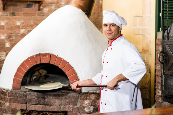 Chef legt Teig für Pizzen in den Ofen, — Stockfoto