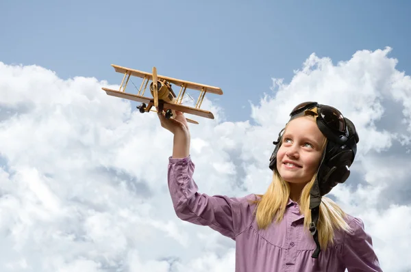 Дівчина в шоломі пілот грає з іграшковим літаком — стокове фото