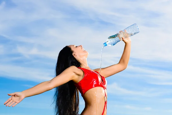 Sport meisje in rood pak met een fles water — Stockfoto