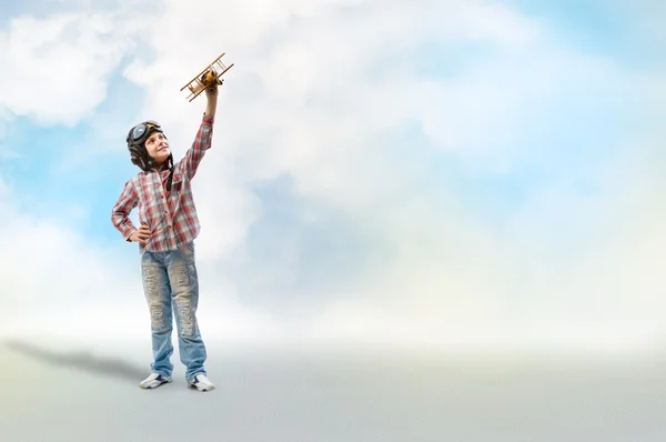 Menino no piloto de capacete brincando com um avião de brinquedo — Fotografia de Stock