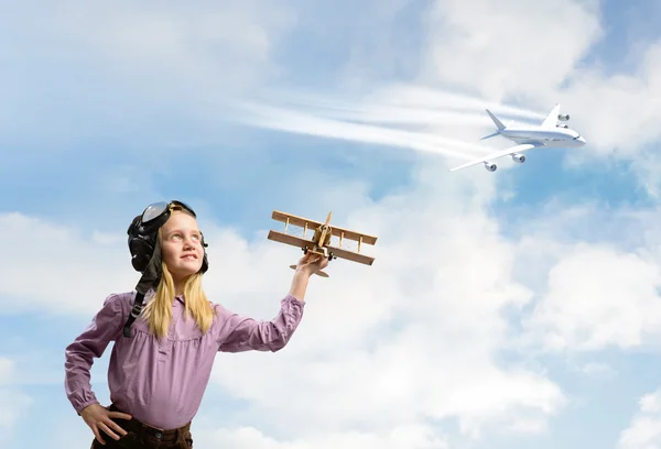 Ragazza in casco pilota giocare con un aeroplano giocattolo — Foto Stock