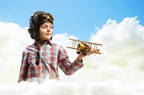 Garçon dans casque pilote jouer avec un jouet avion — Photo