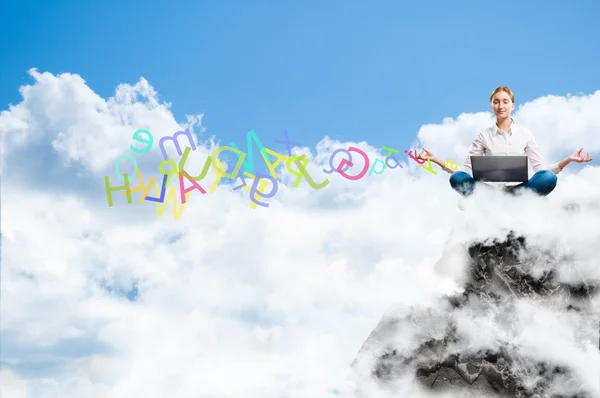 Mujer joven meditando con un portátil en una roca — Foto de Stock