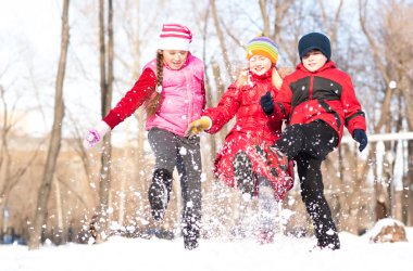 Boy and girls playing with snow in winter park