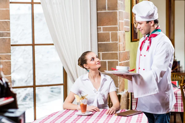 Chef brings a dish pretty woman in a restaurant — Stock Photo, Image