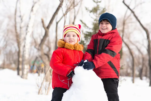 Boy and girl playing with snow in winter park — Stock Photo, Image