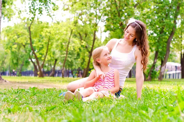 母と娘は草の上に一緒に座っています。 — ストック写真